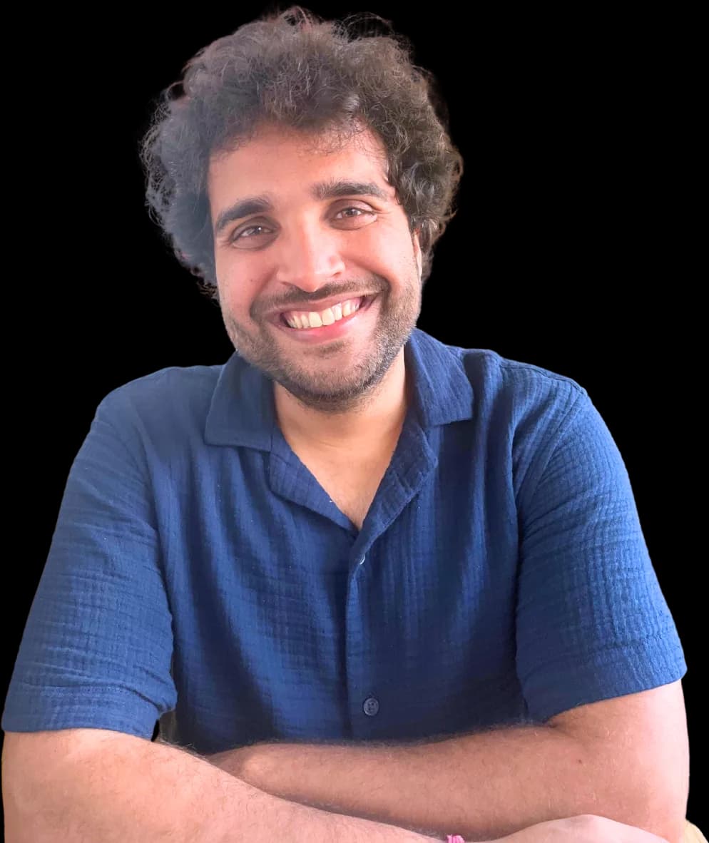Aditya smiling at the camera, arms folded, in a navy shirt.