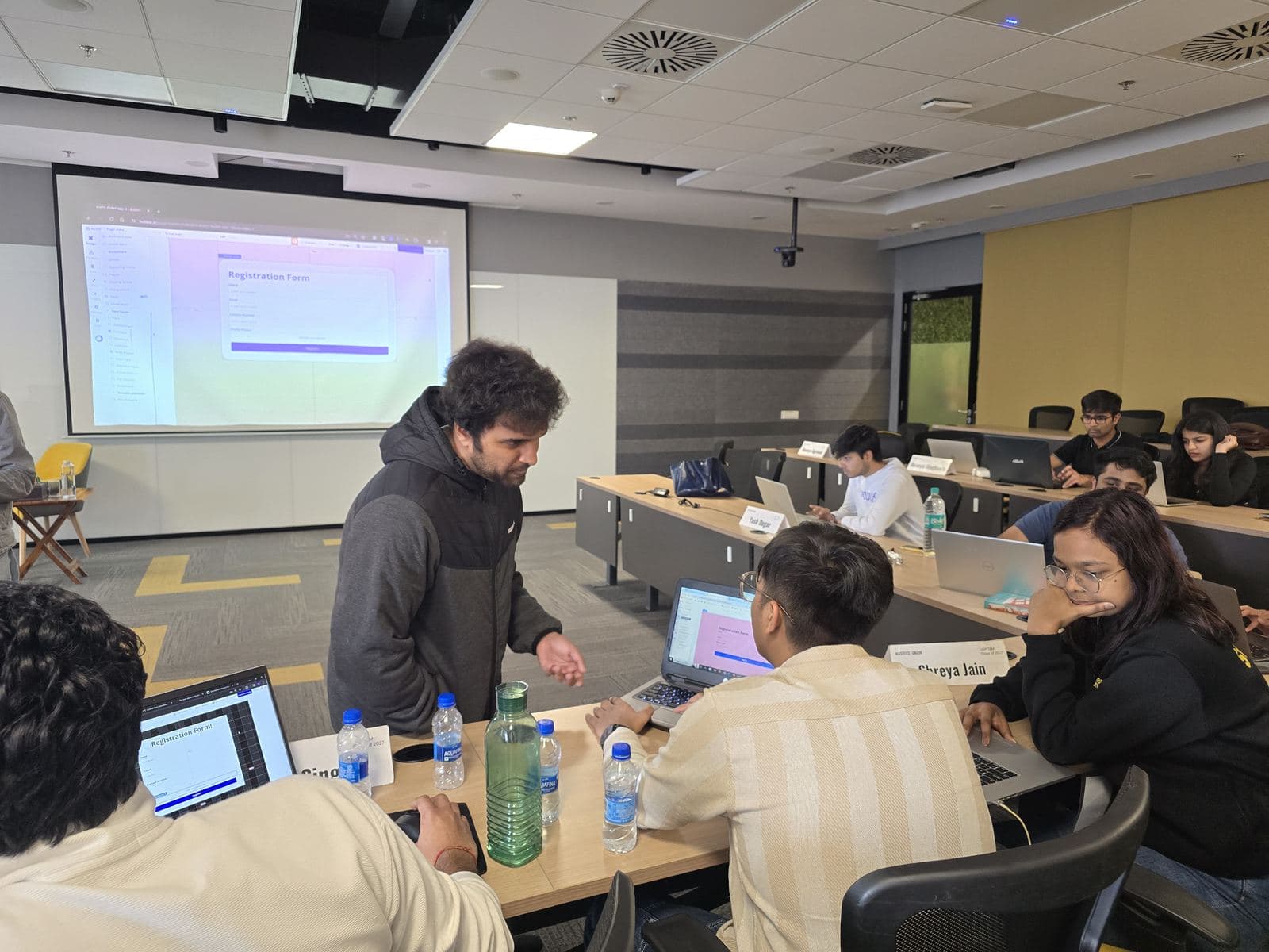 Adi helping a student at their laptop during an in-person AI building session.